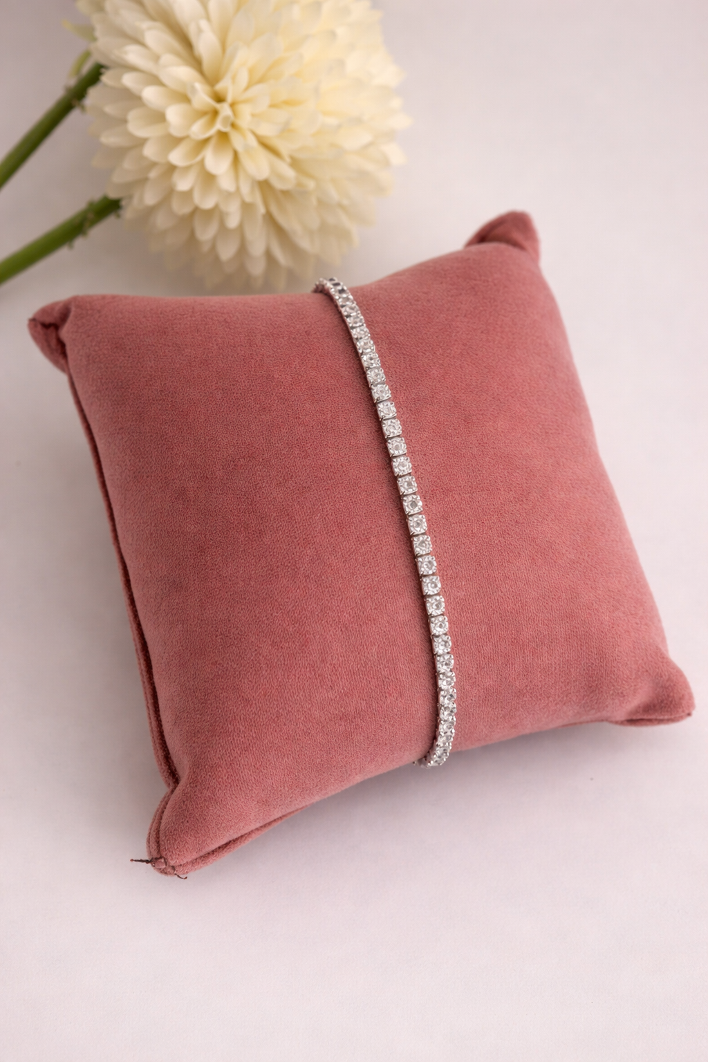 Bracelet on a pink pillow with a white flower in the background