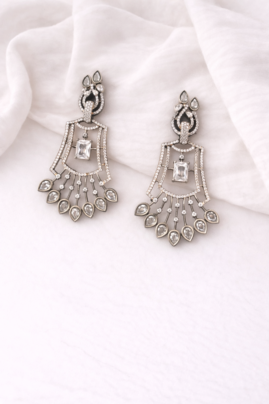 Pair of silver chandelier earrings on a white fabric background
