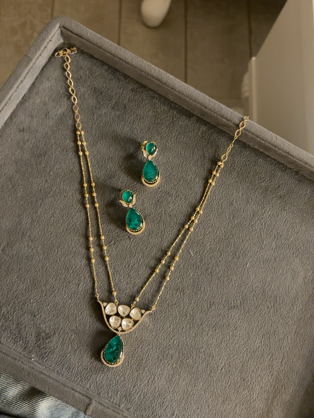 Emerald green kundan pendant necklace set with matching teardrop earrings in a gold finish
