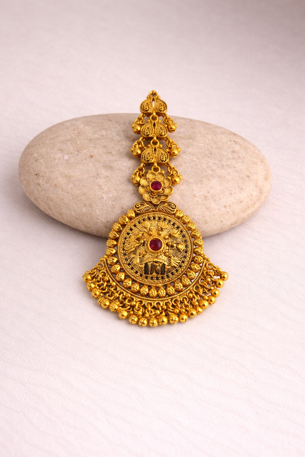 Gold tikka with a red gemstone 