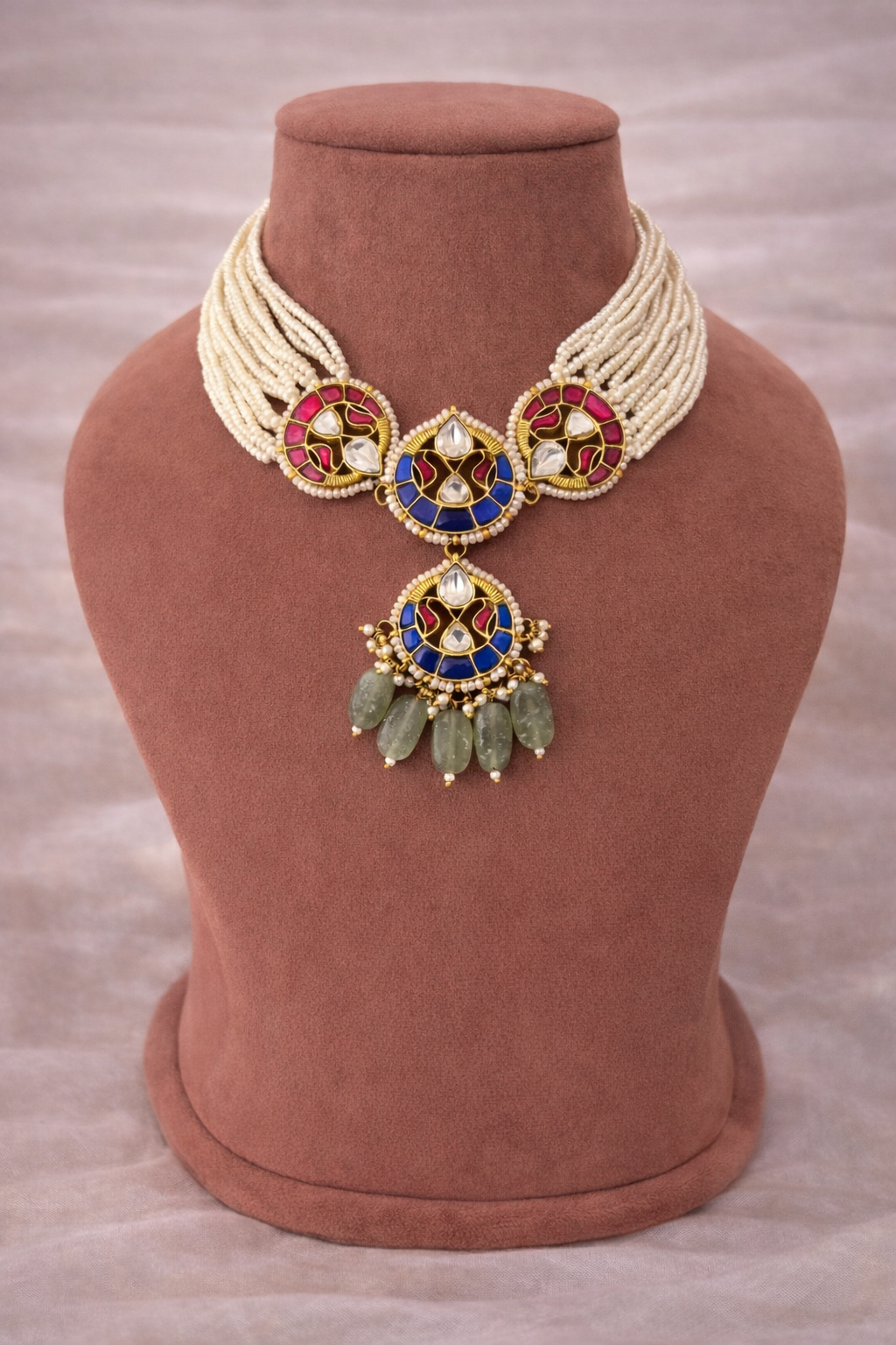 Pair of gold and blue earrings with green beads on a light gray background