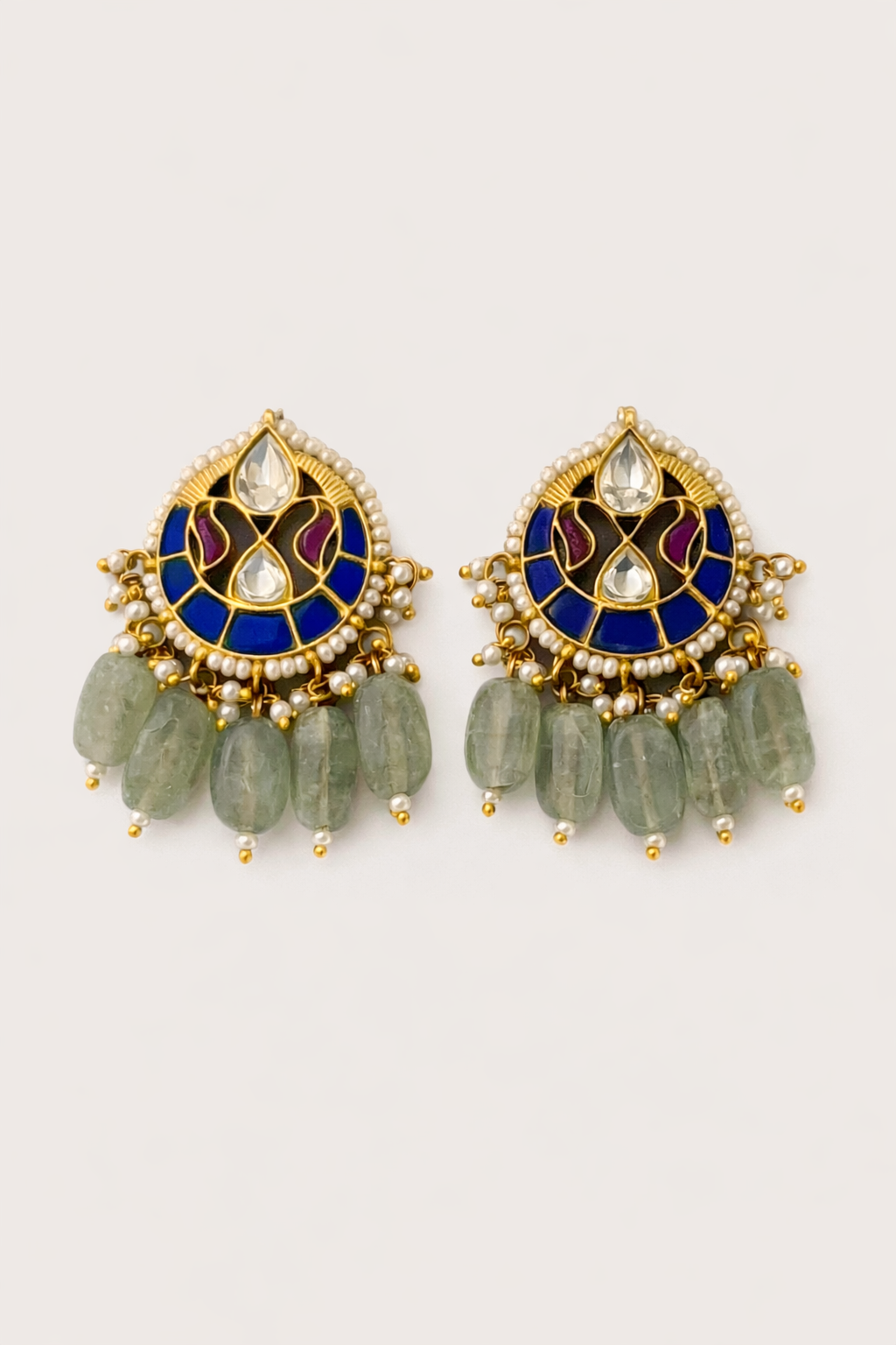 Pair of gold and blue earrings with green beads on a light gray background