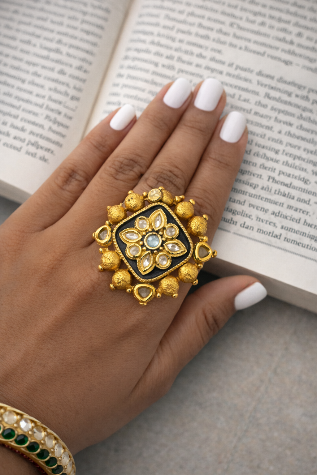 Decorative gold ring on a hand with an open book in the background