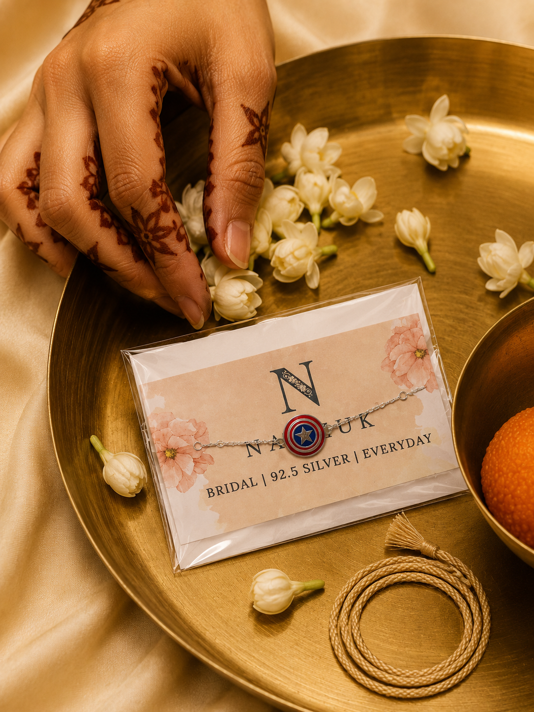 925 Sterling Silver Captain Shield Rakhi bracelet displayed in premium festive packaging on a brass thali with jasmine flowers for Raksha Bandhan gifting.