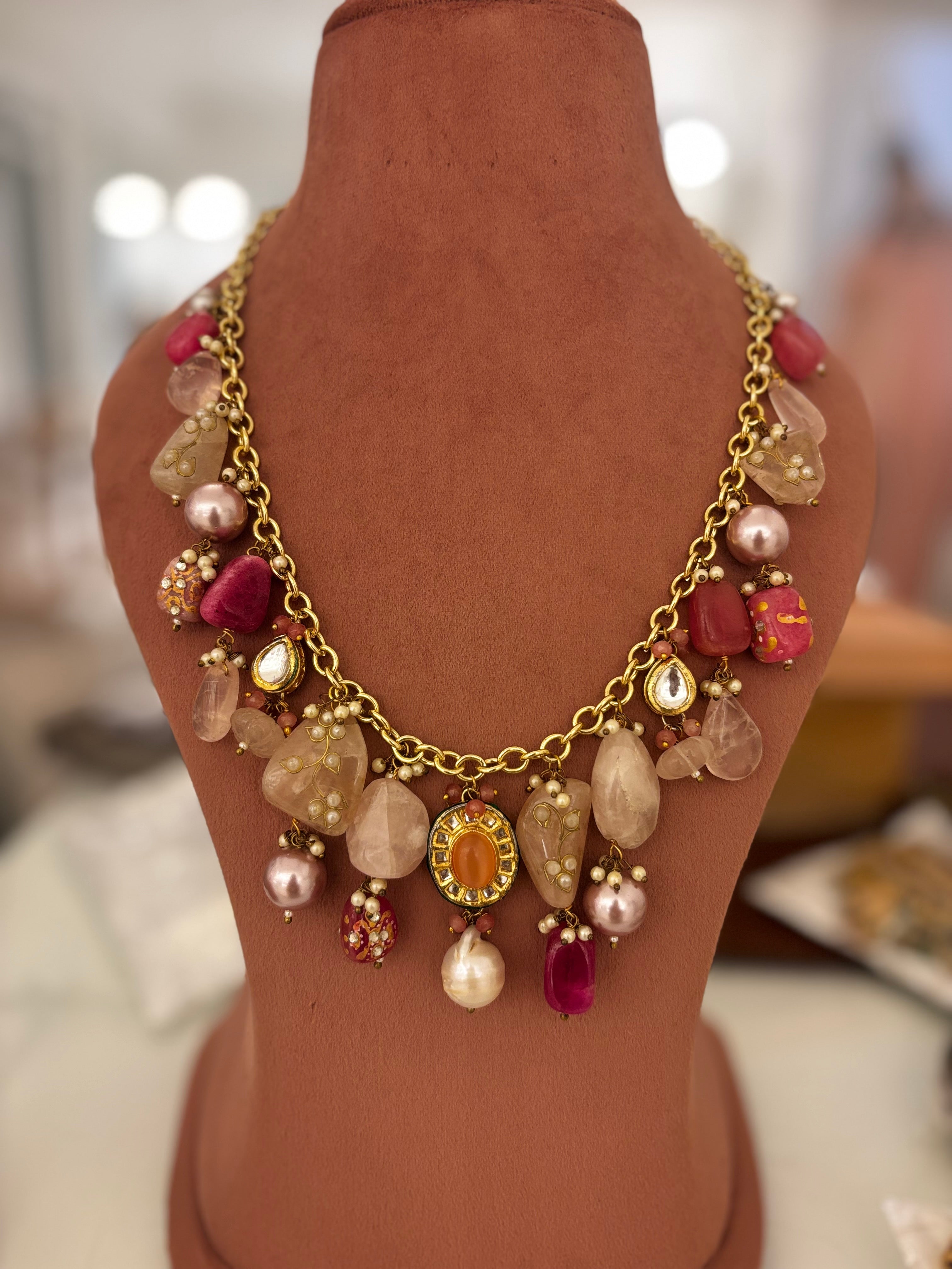 Necklace with multicolored beads and gold chain on a mannequin bust.