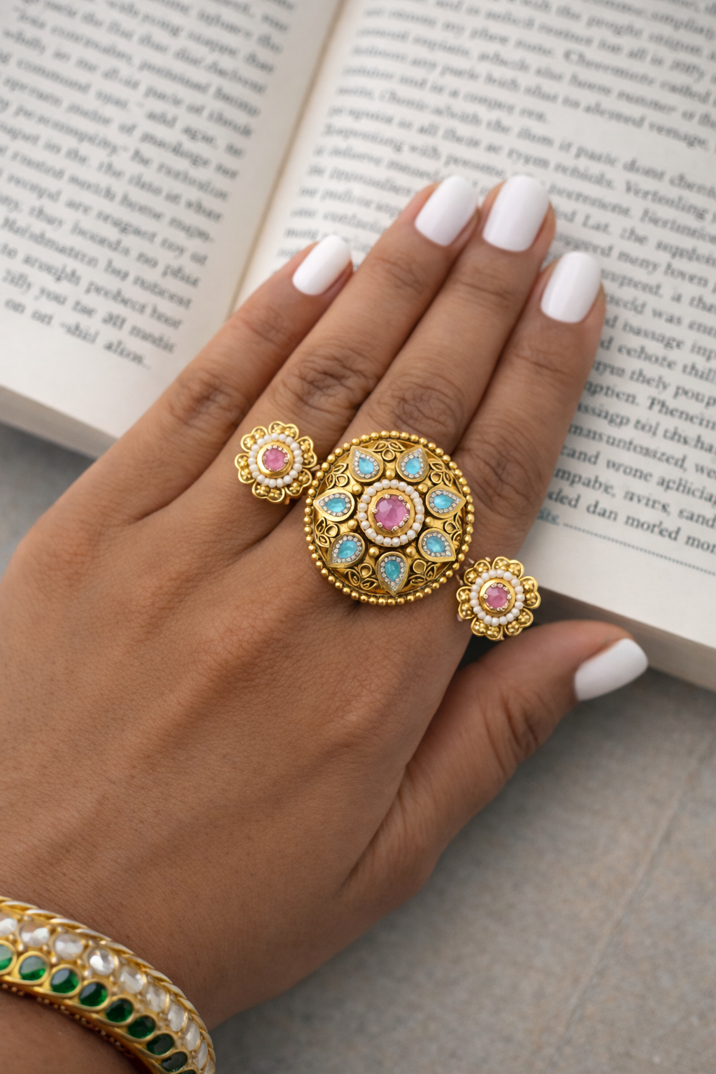 Hand wearing gold rings with gemstones on an open book
