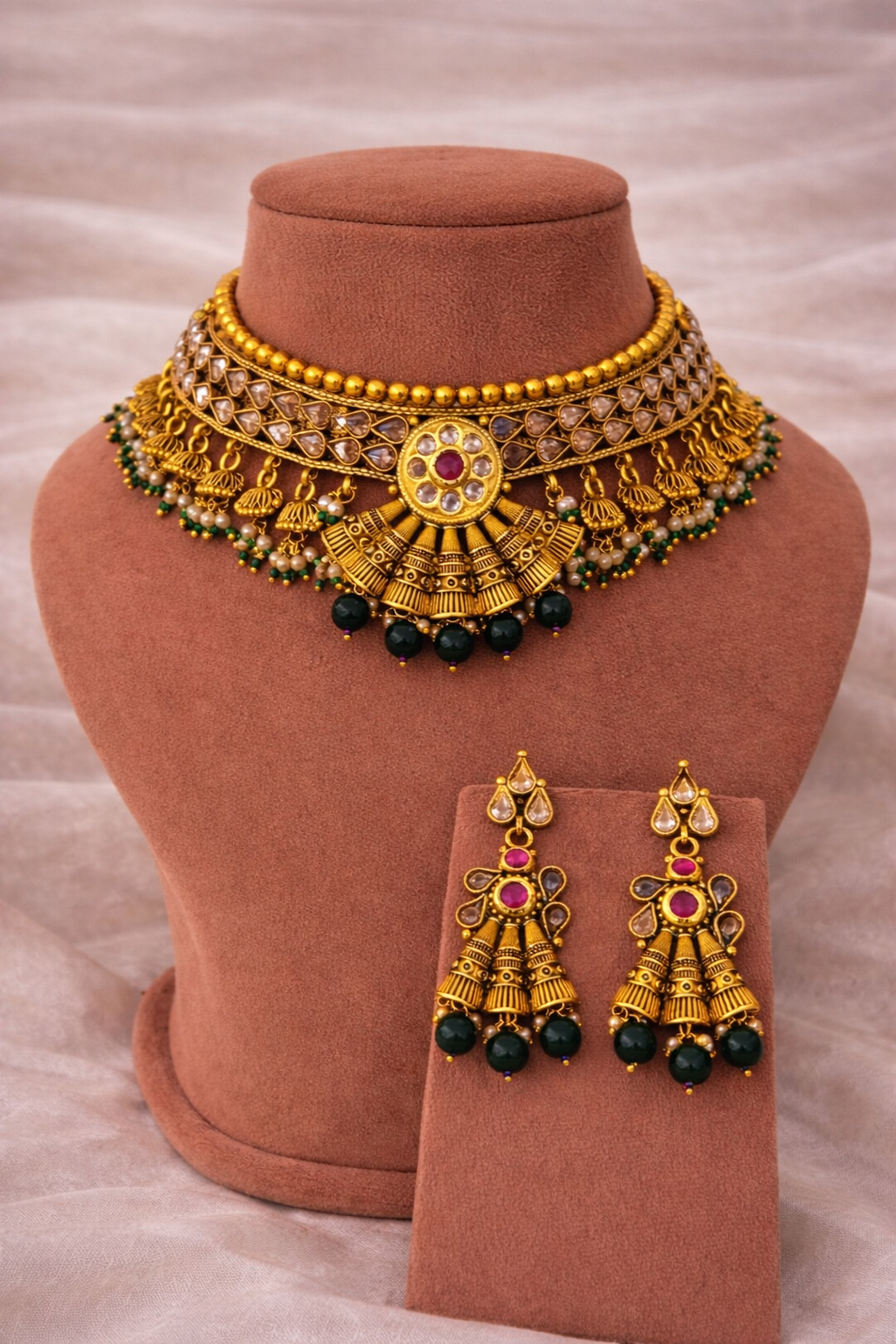 Gold jewelry set with necklace and earrings on a brown mannequin bust.