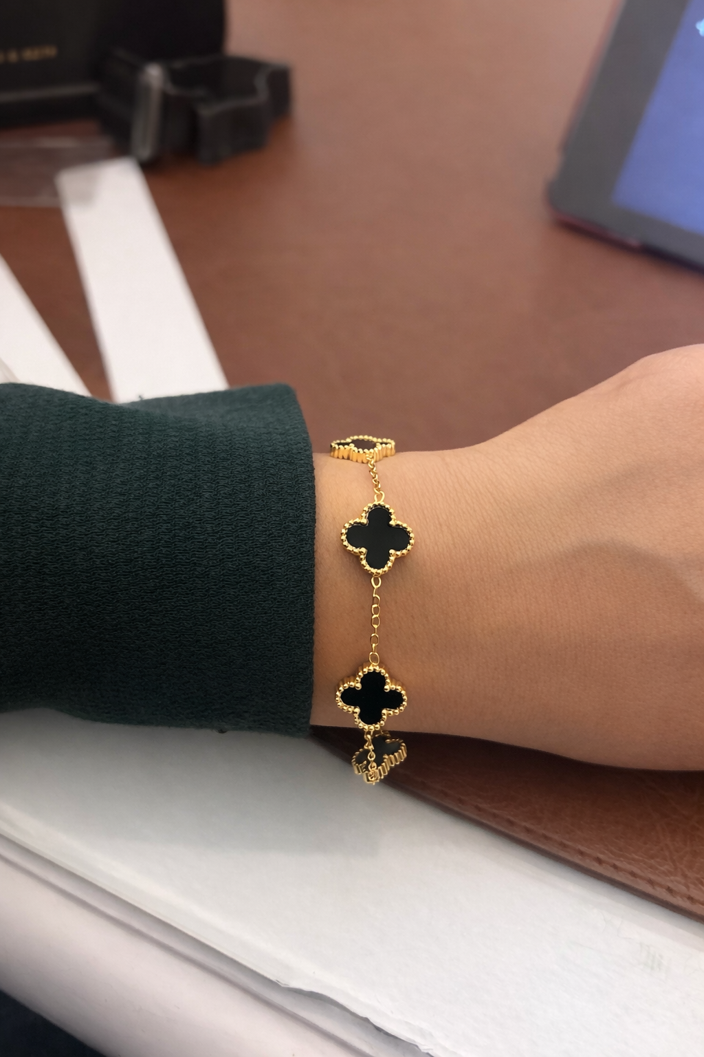 Gold bracelet with green gemstones on a wrist against a blurred background