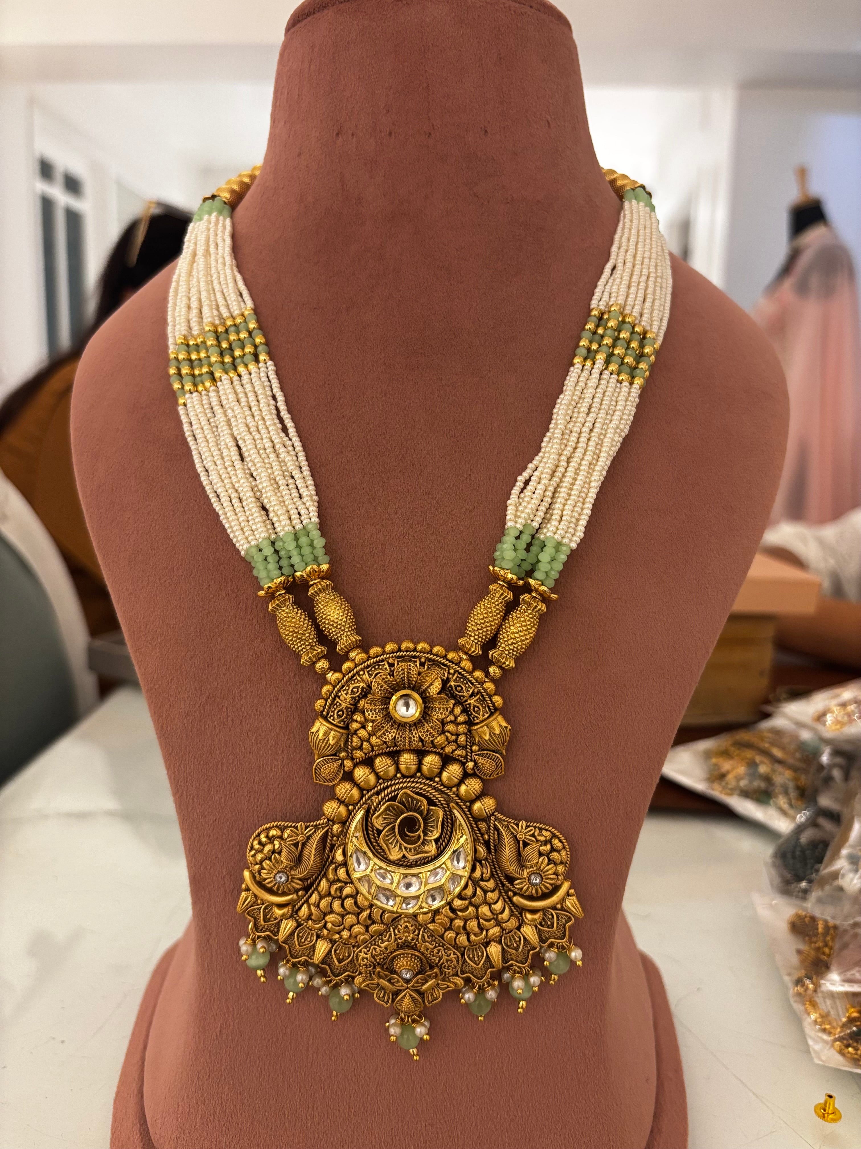 Ornate gold necklace with beads on a mannequin bust