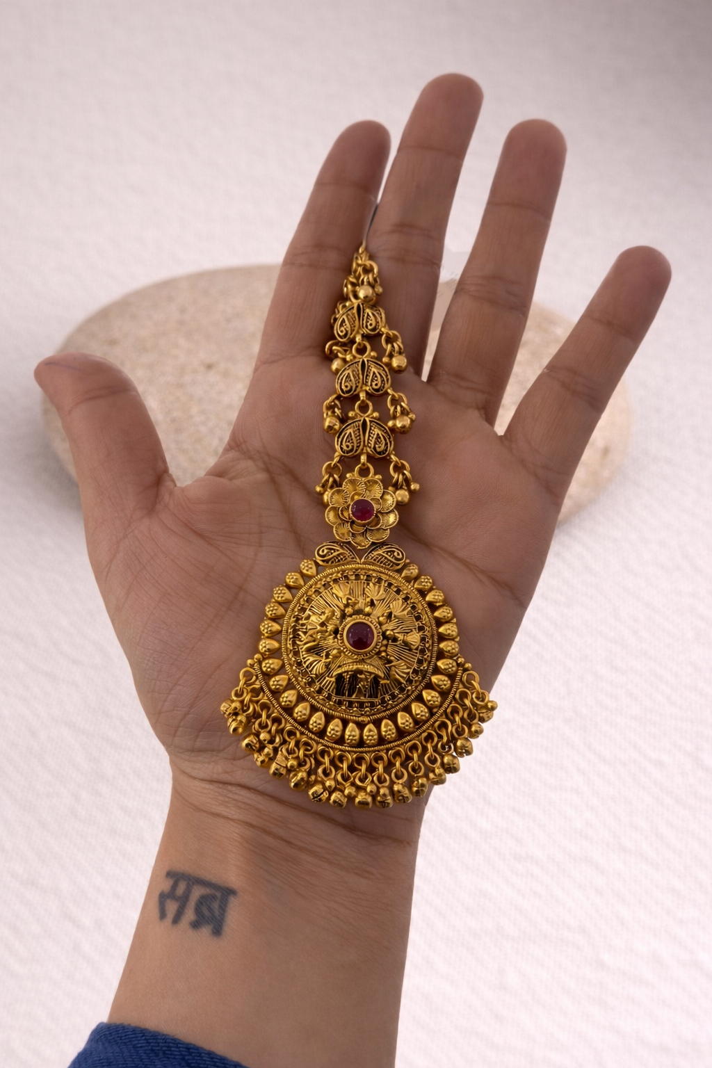 Gold tikka with a red gemstone 