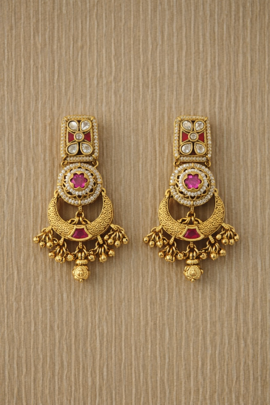 Pair of gold earrings with gemstones on a beige background