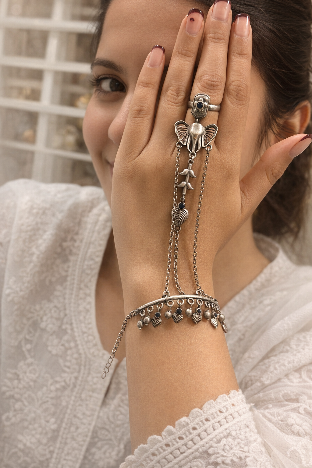 Woman wearing a silver bracelet with chain details on a neutral background