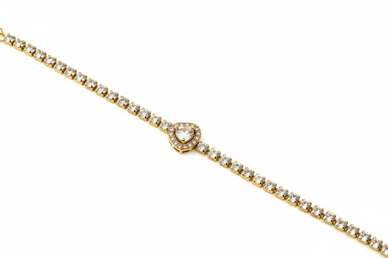 Gold bracelet with heart-shaped clasp on a red jewelry roll against a light background