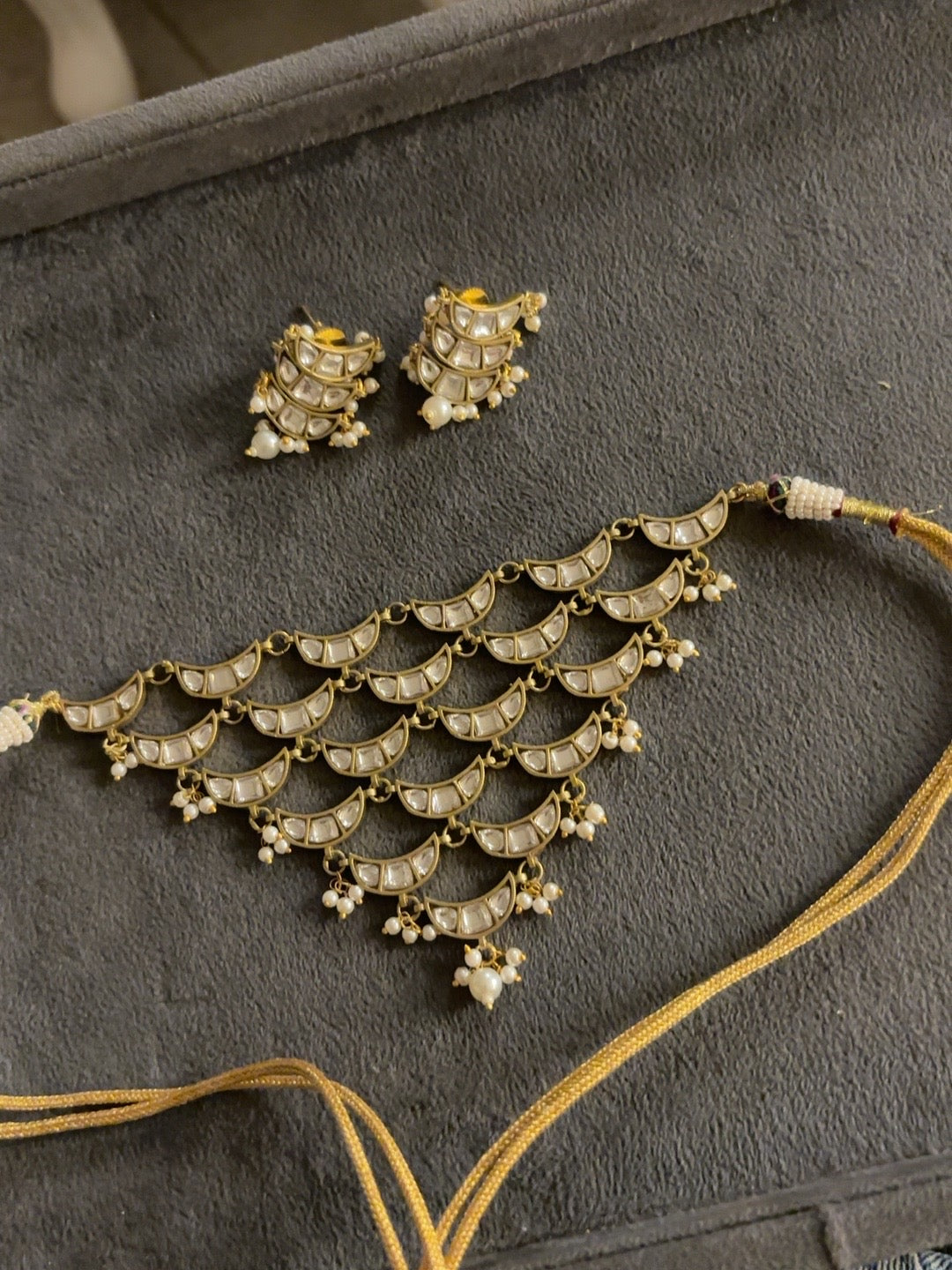 Layered crescent kundan choker set with pearl accents and matching stud earrings in antique gold finish
