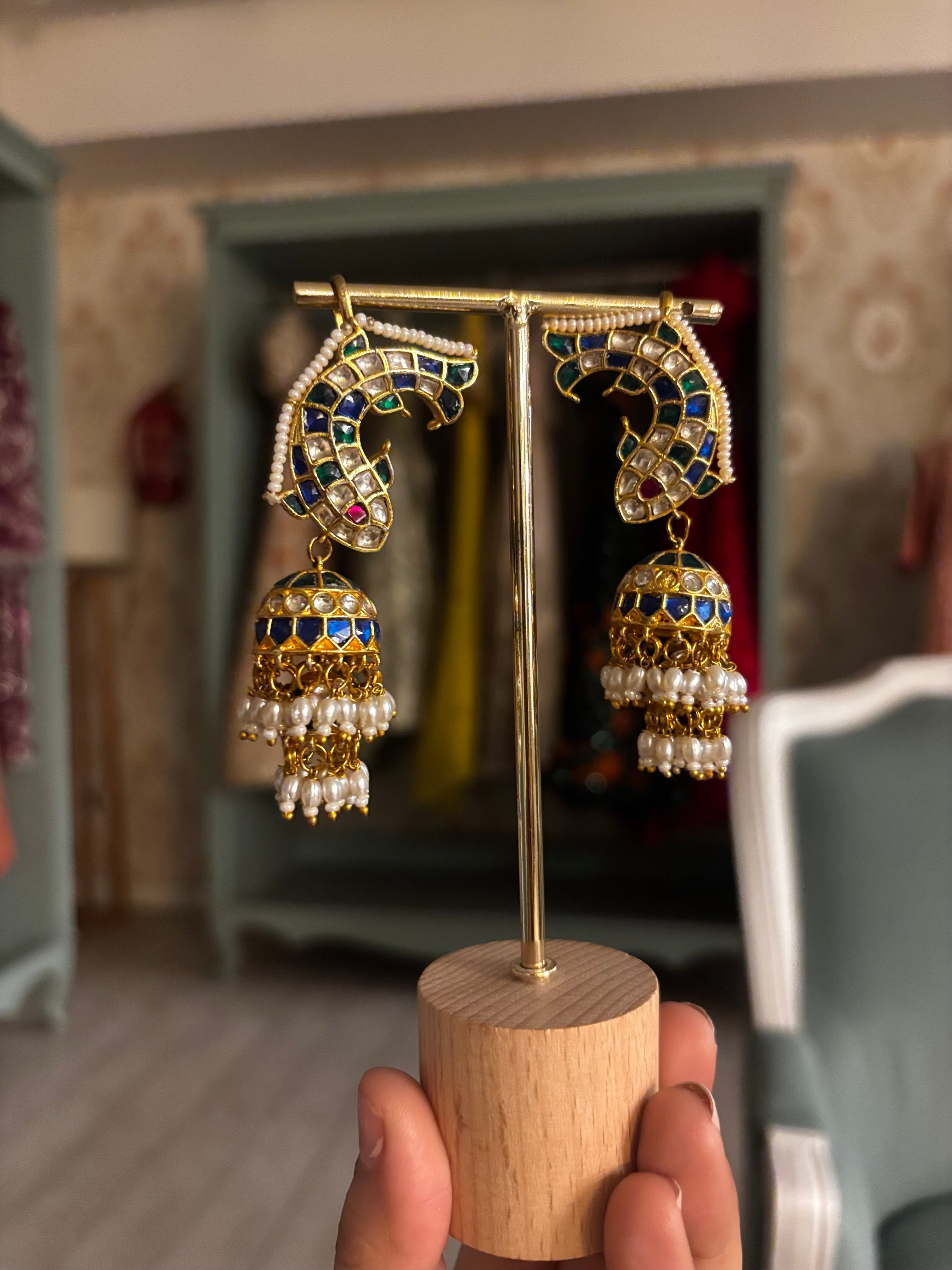 Royal meenakari kundan jhumka earrings with blue enamel detailing and pearl tassels.