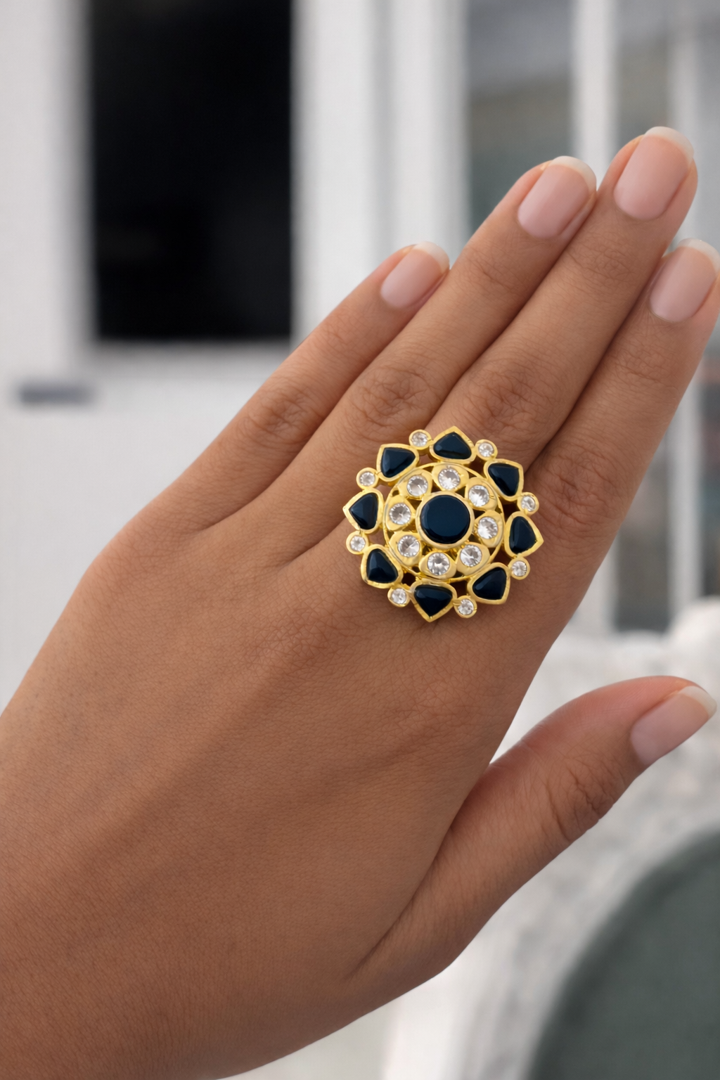 Close-up of a hand wearing a decorative ring with blue and gold design.