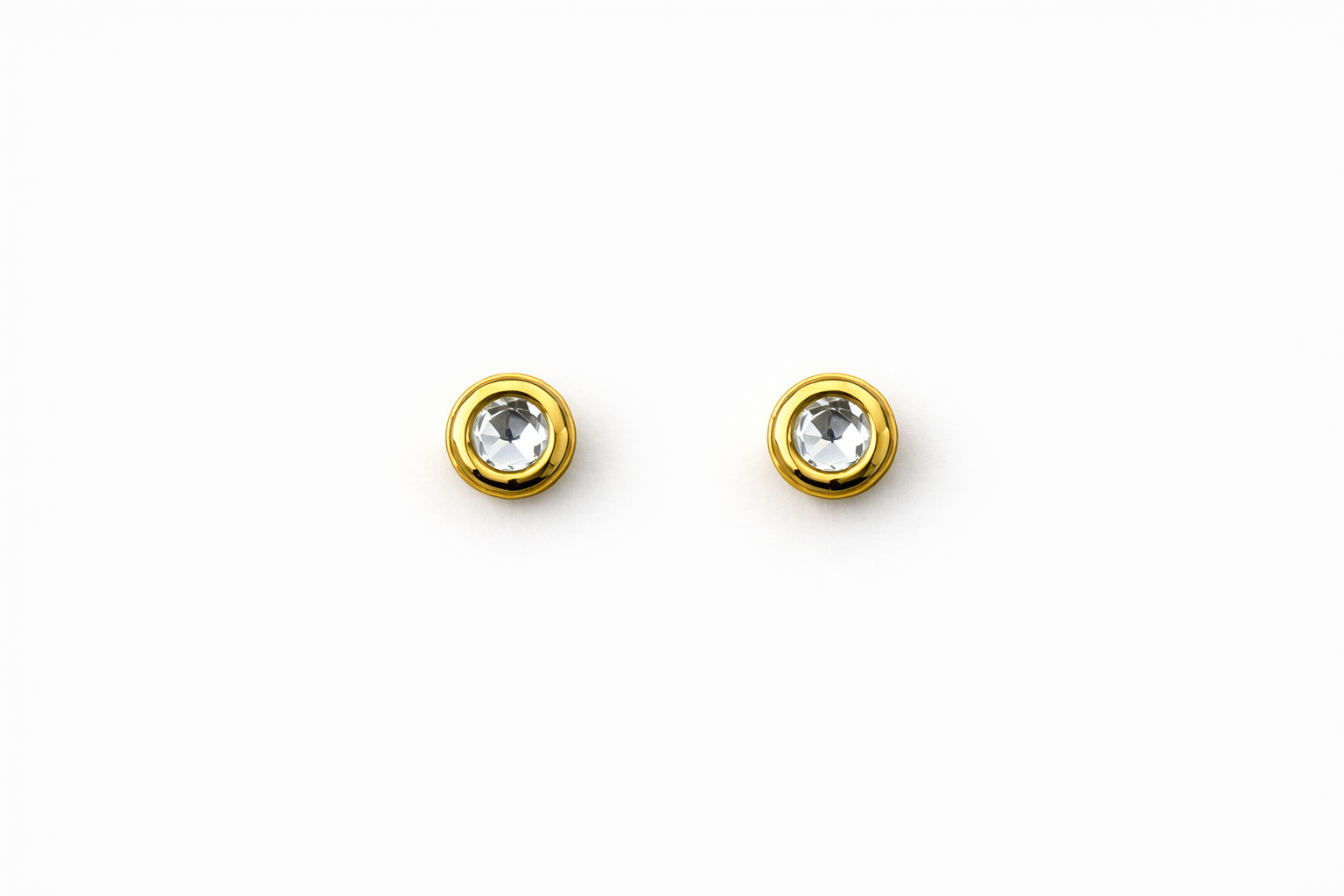 Pair of gold earrings with clear gemstones on a white background