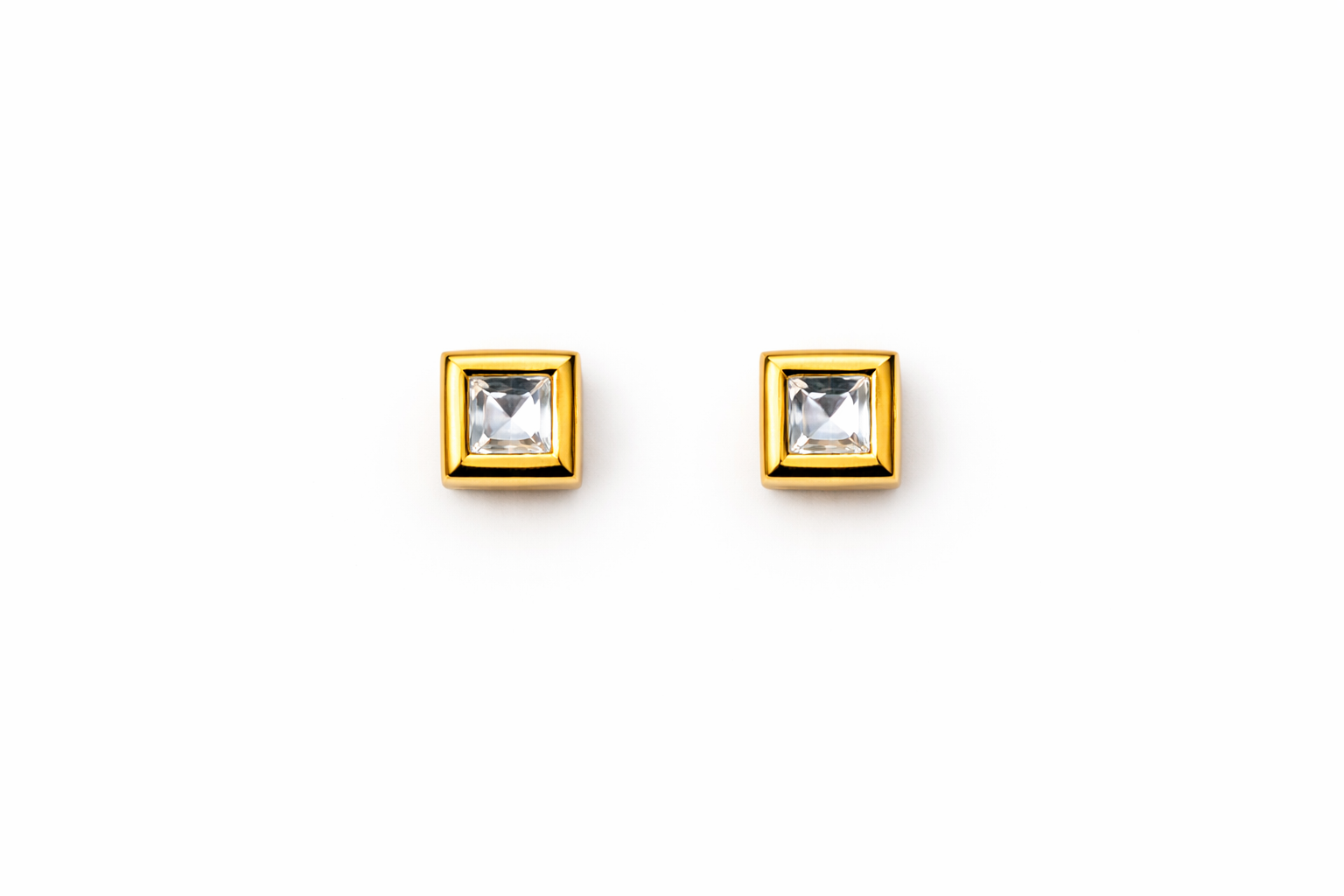 Pair of gold square stud earrings with clear gemstones on a white background