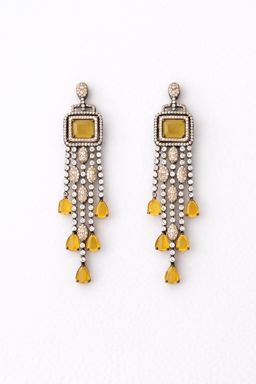 Pair of silver earrings with green gemstones on a white fabric background