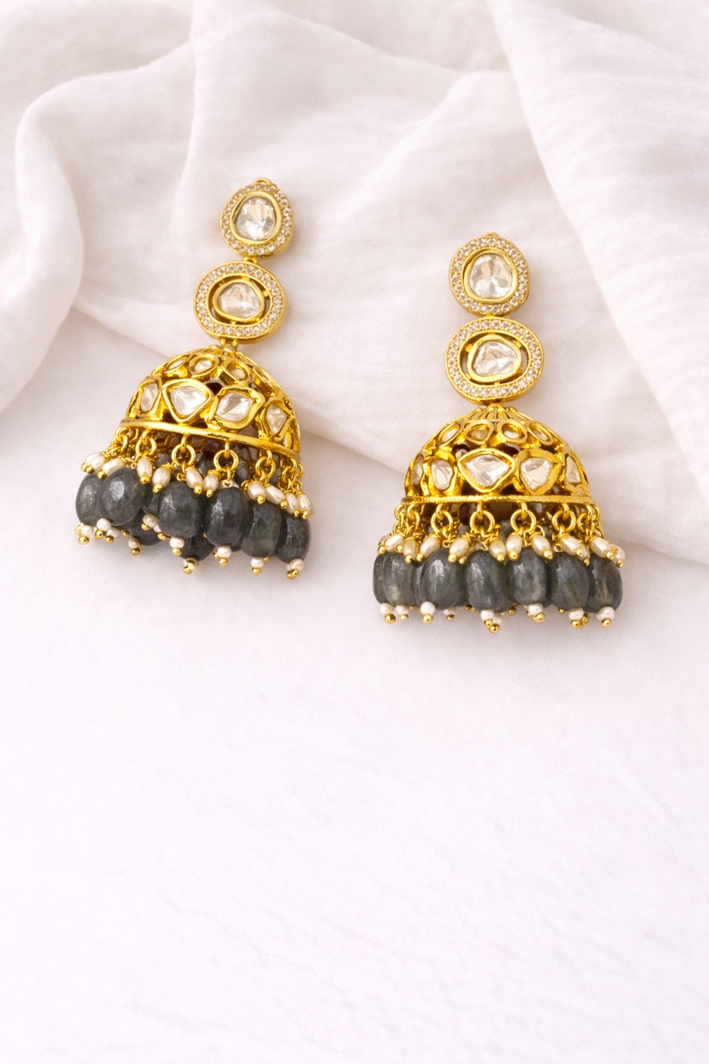 Gold and silver beaded earrings on a white fabric background