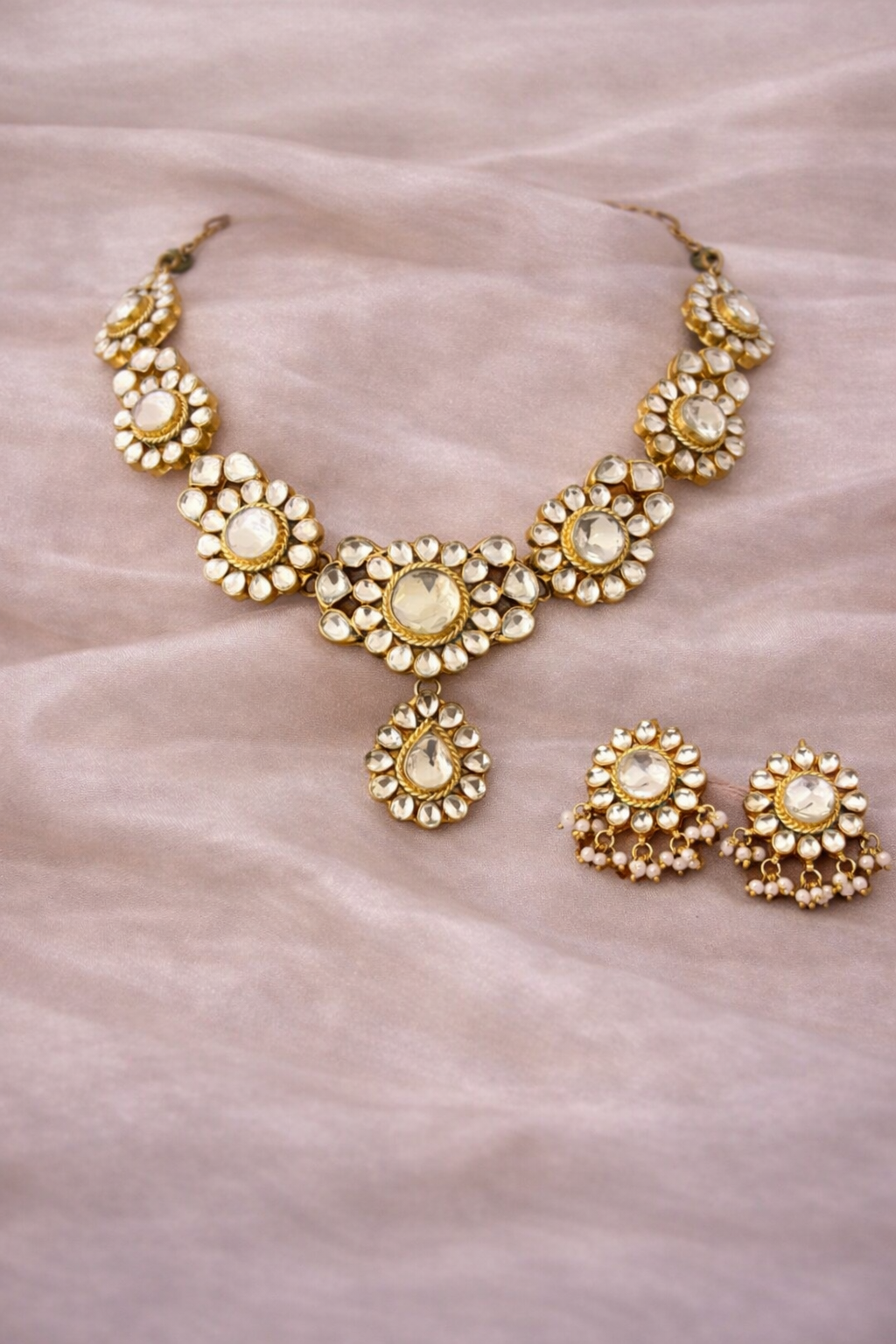 Gold necklace and earrings on a textured beige background