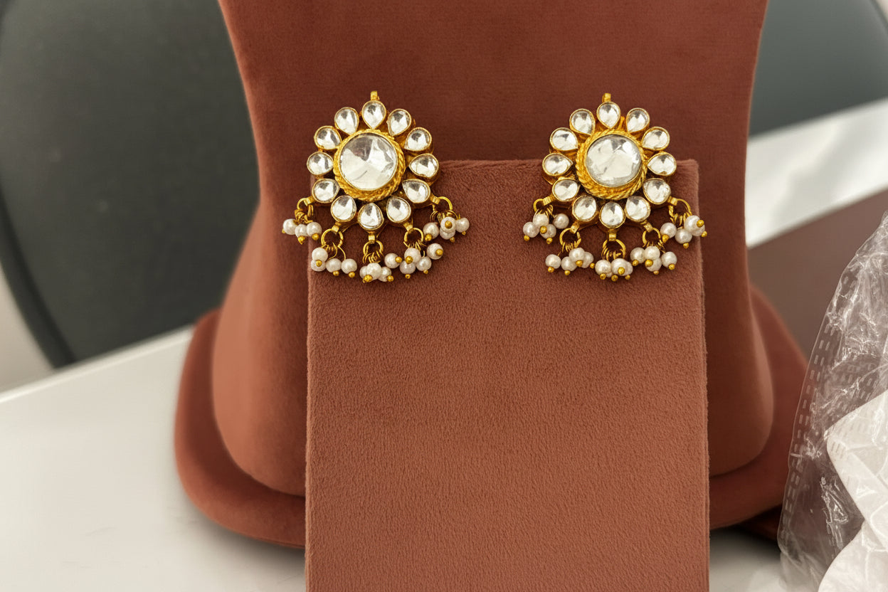 Gold necklace and earrings on a textured beige background
