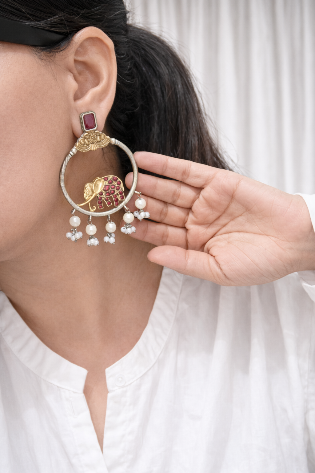 Close-up of a person wearing a decorative earring with a hand adjusting it.